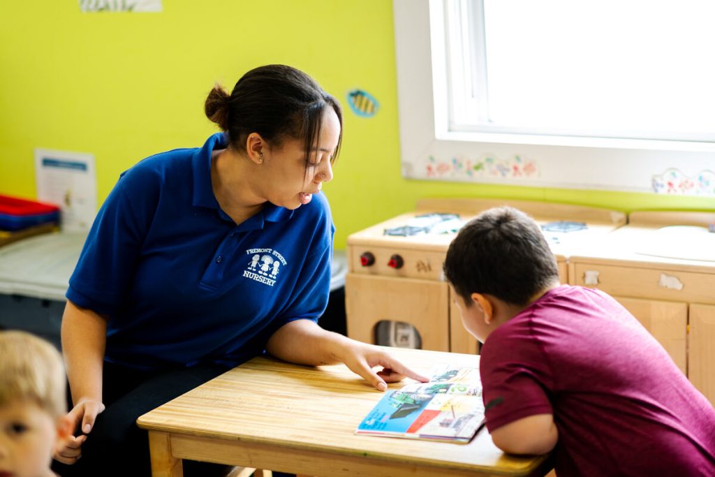 A woman sits and teaches a small boy.