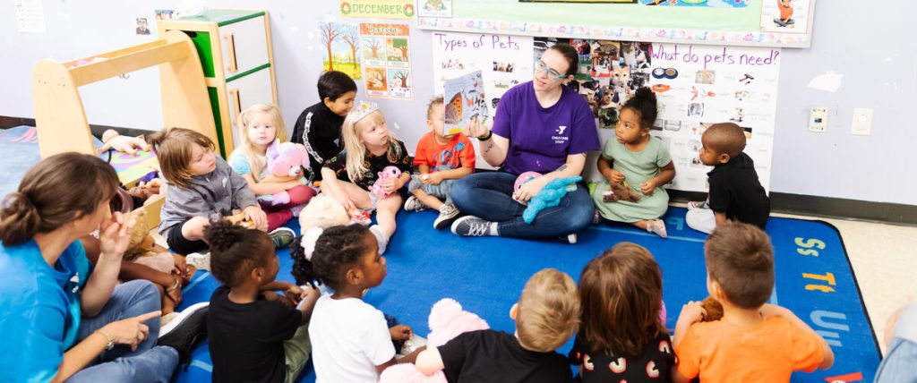 A woman sits on a mat surrounded by children.